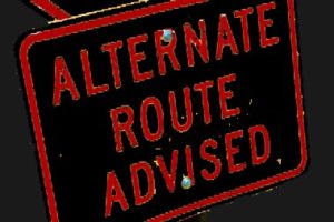 Black road sign with red text: Alternate route advised.