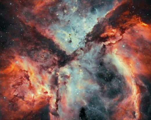 Close up of the Carina Nebula that looks like vividly coloured clouds full of stars.